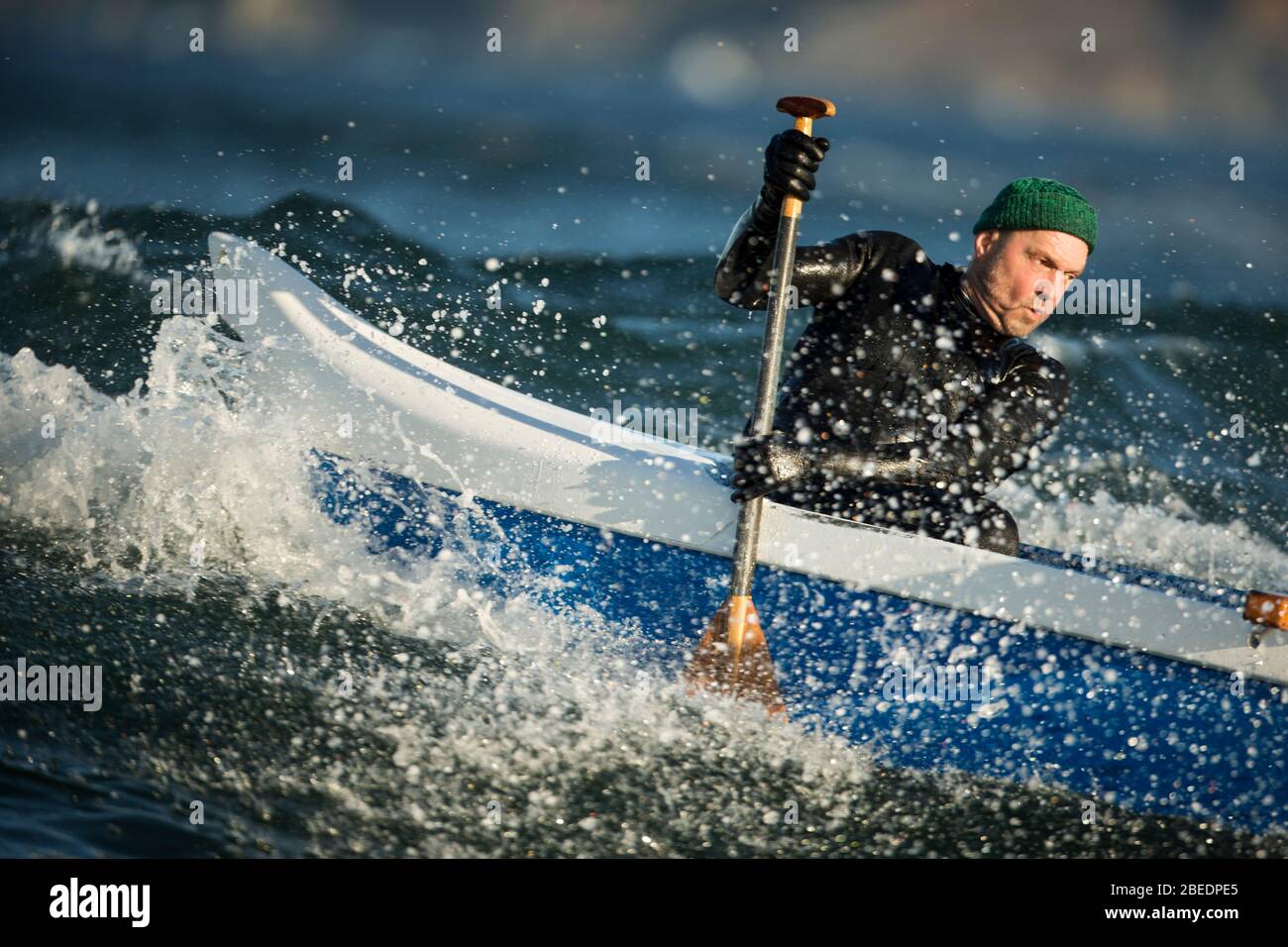One man in an outrigger canoe in choppy ocean waves Stock Photo