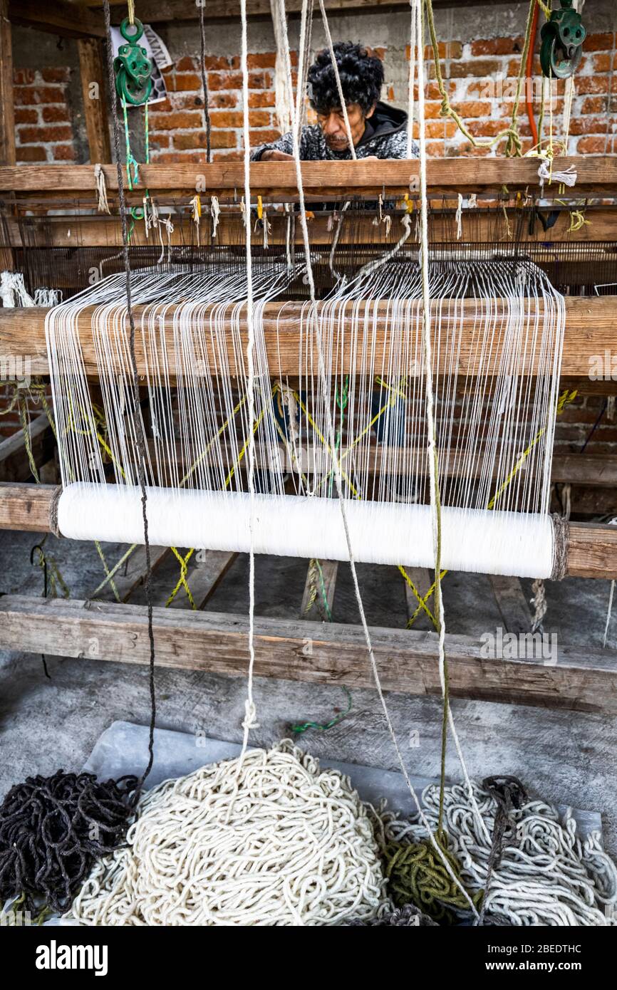 An artisan works the loom in a San Miguel de Allende textile shop in Mexico. Stock Photo