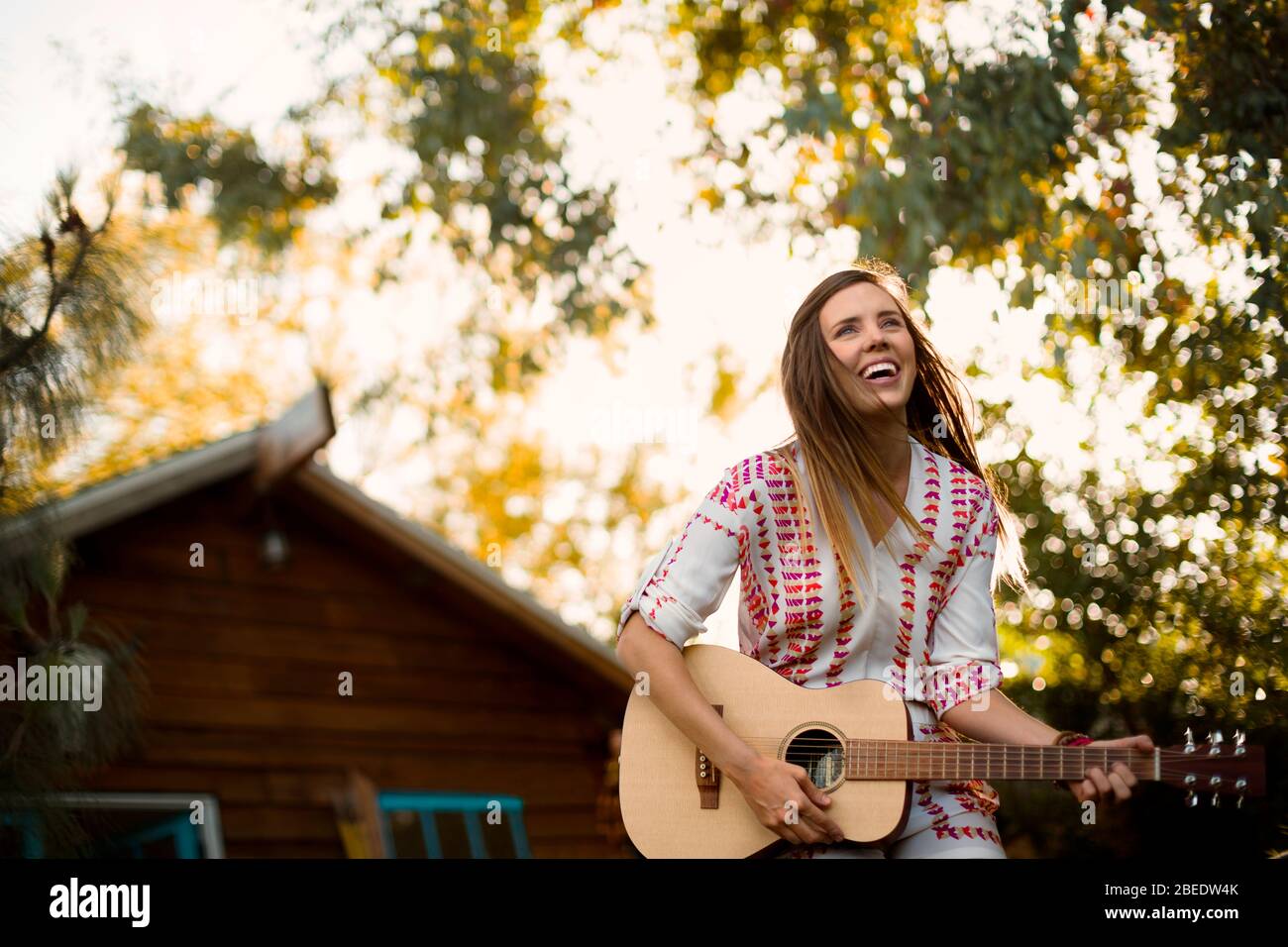 Young woman playing an acoustic guitar outdoors Stock Photo - Alamy
