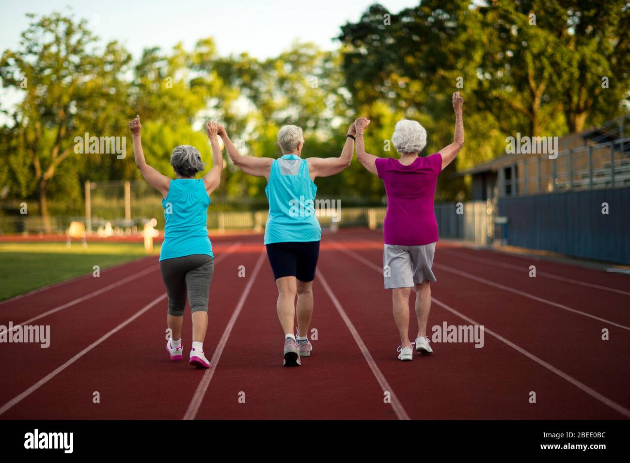 Senior women holding hands while walking on an athletic track Stock Photo