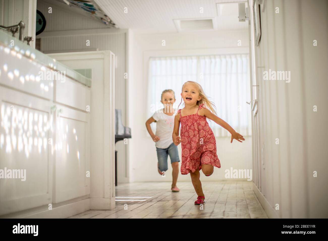 Two little girls have fun running through the house together Stock Photo
