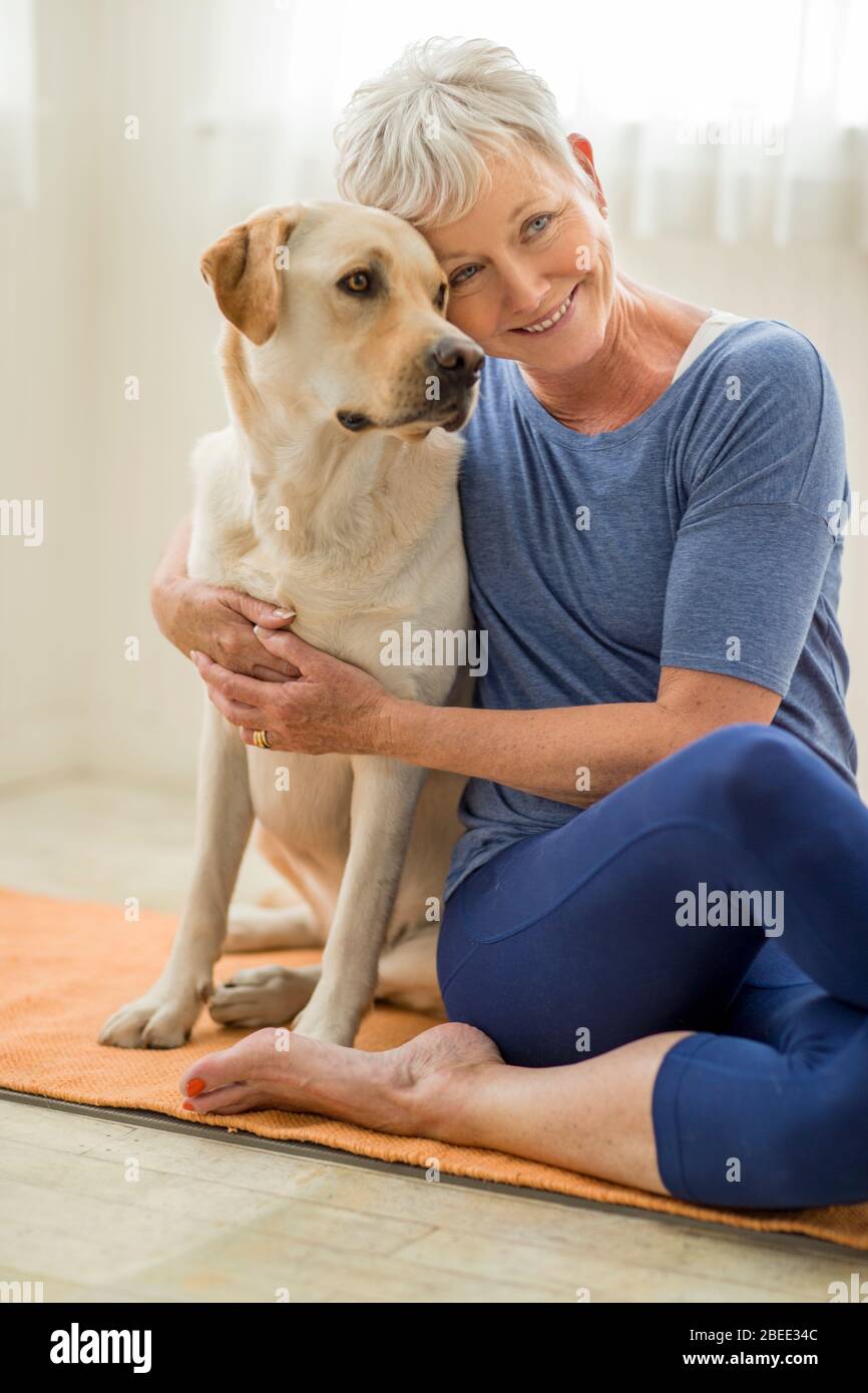 Happy mature woman hugging her dog on a mat Stock Photo