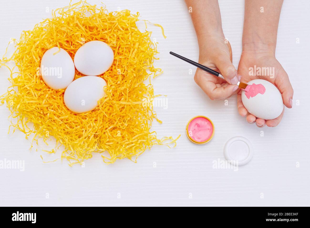 Happy easter! child's hand painting Easter eggs on wooden white table. Painting eggs for easter holiday celebration. Stock Photo