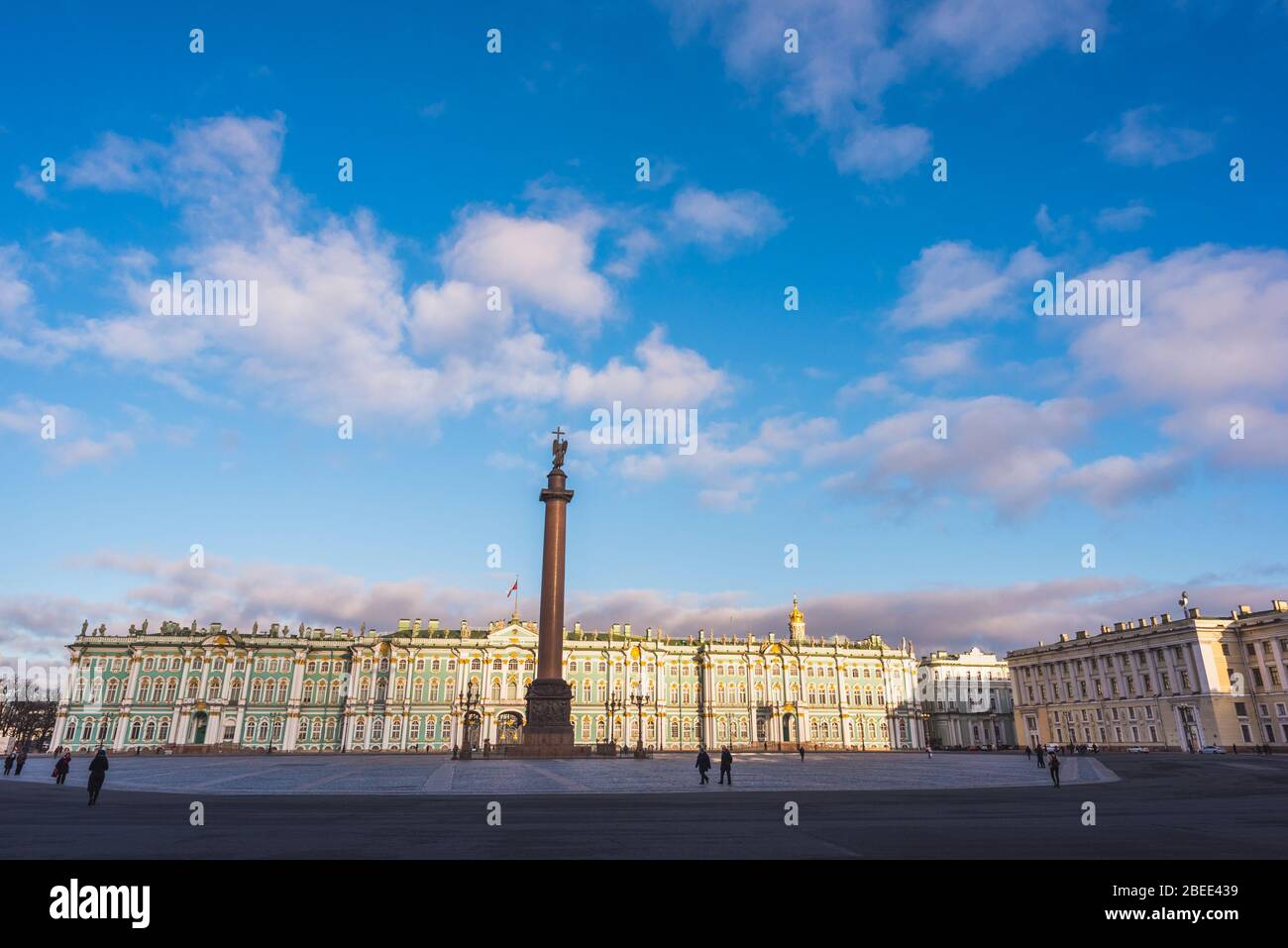 Palace Square, Alexander Column and the Hermitage. People (unrecognizable) walking and the blue sky above - Saint Petersburg, Russia. Stock Photo