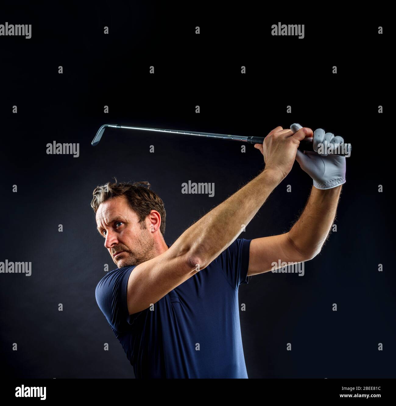Close-up of a golf player intent on perfecting the swing isolated on black background Stock Photo