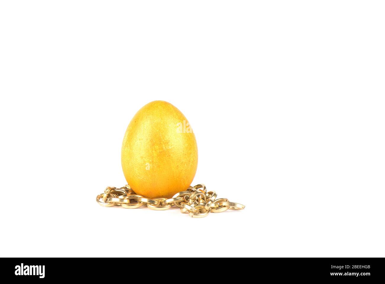 Golden easter egg on a gold chain over a white background. Copy space. Stock Photo