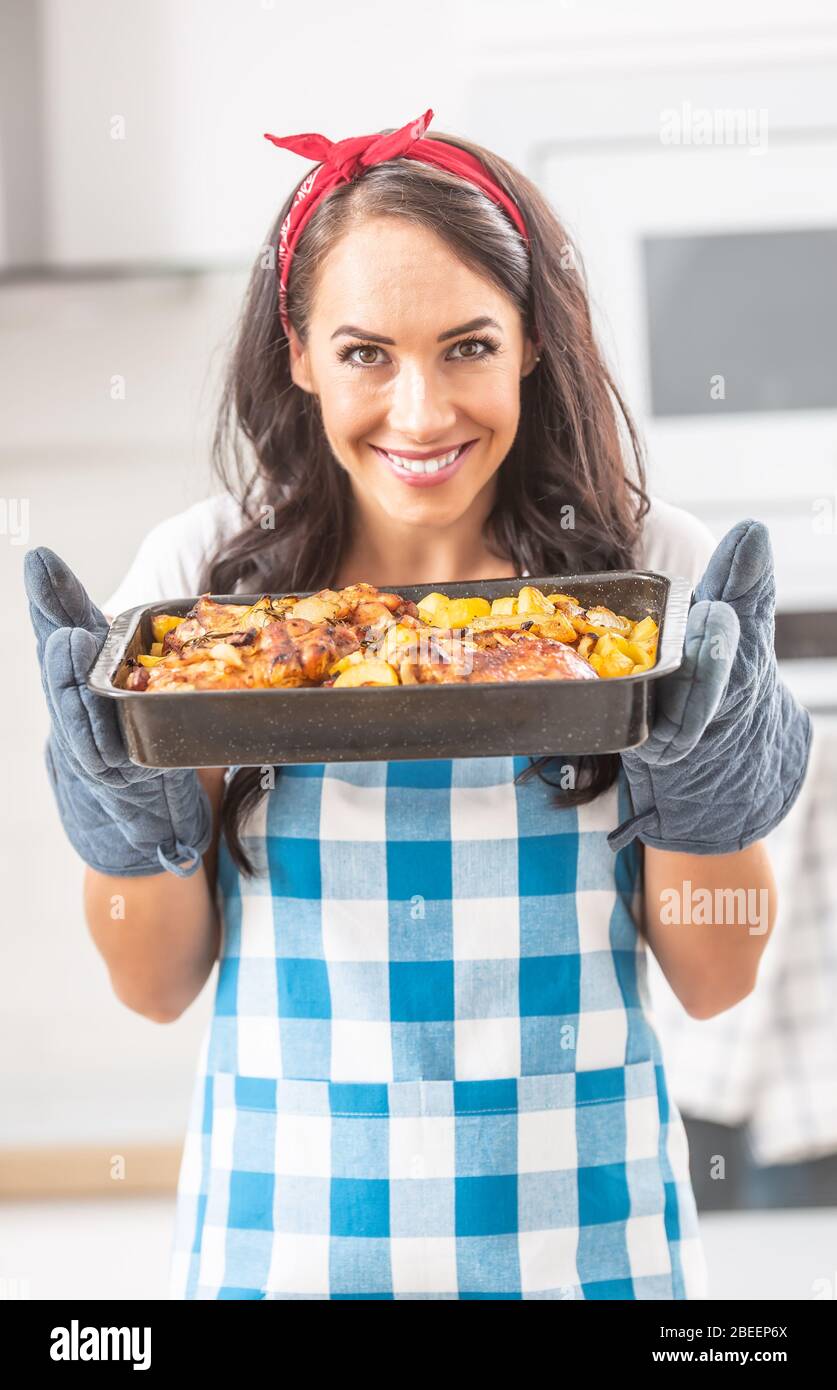 Beautiful wife holding a steaming hot tray in the kitchen, holding