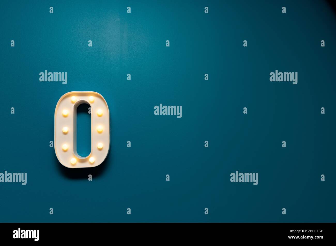 Single Light up Letter "O" on Teal wall, conceptual Stock Photo Alamy