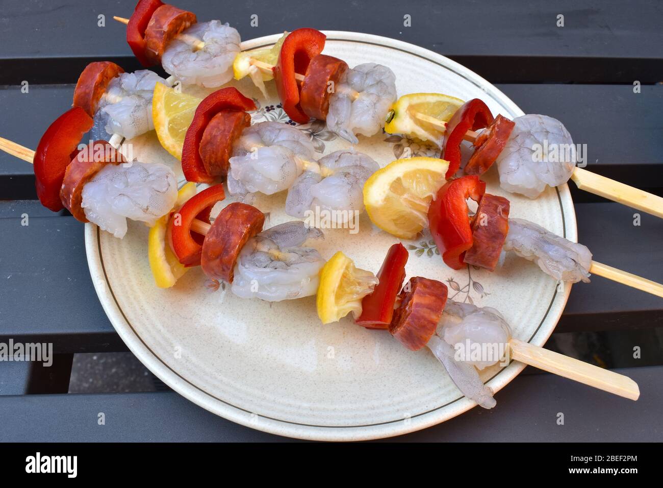 Raw juicy king prawn skewers with lemon and red pepper ready to be