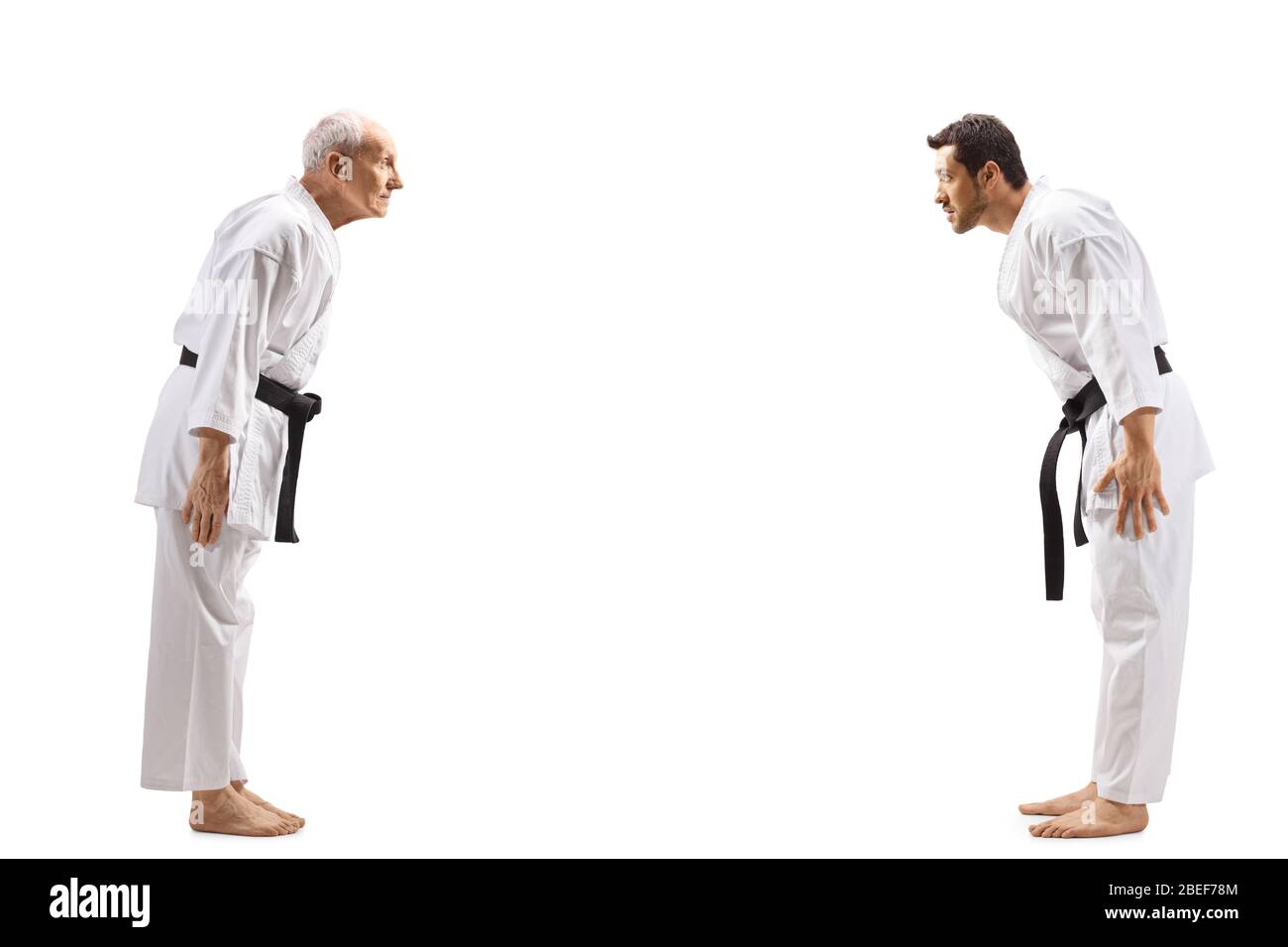 Full length profile shot of young man and elderly man in karate kimonos bowing isolated on white background Stock Photo