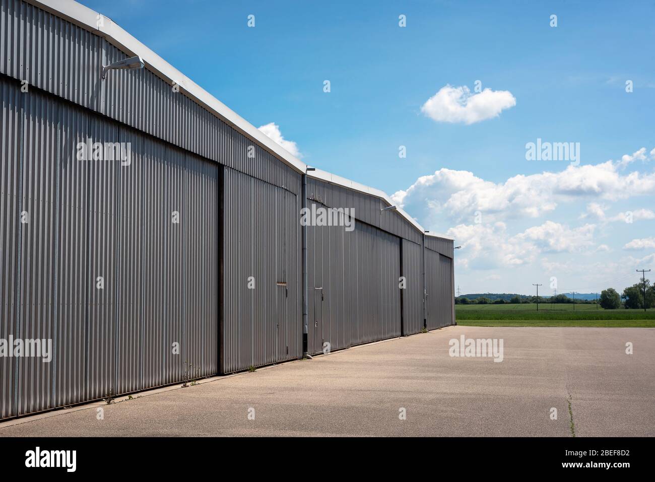 Metal structure hangar from a private airport in Germany. Hangar exterior view on a beautiful summer day. Private airport hangar. Stock Photo