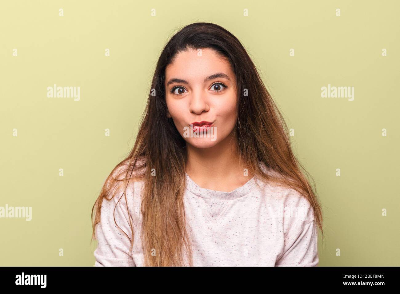 portrait of cheerful young woman brunette with big eyes with black eyeliner  making funny face against yellow background Stock Photo - Alamy