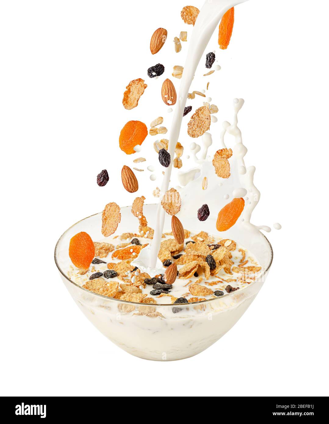 Pouring milk and falling muesli over a transparent bowl. Isolated on white. Healthy breakfast Stock Photo