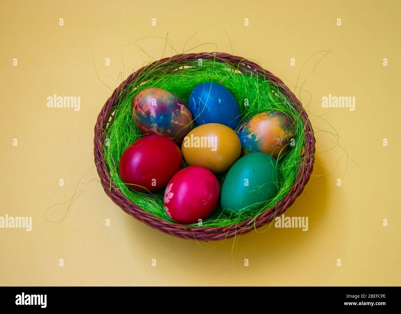 Green grass nest in a basket with colored chicken Easter eggs ...