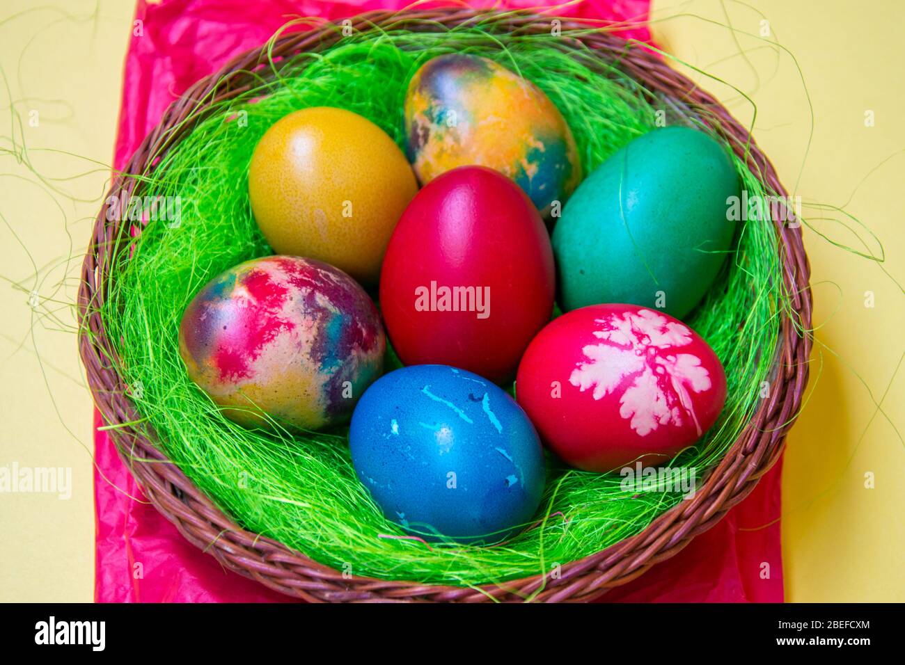 Green grass nest in a basket with colored chicken Easter eggs ...