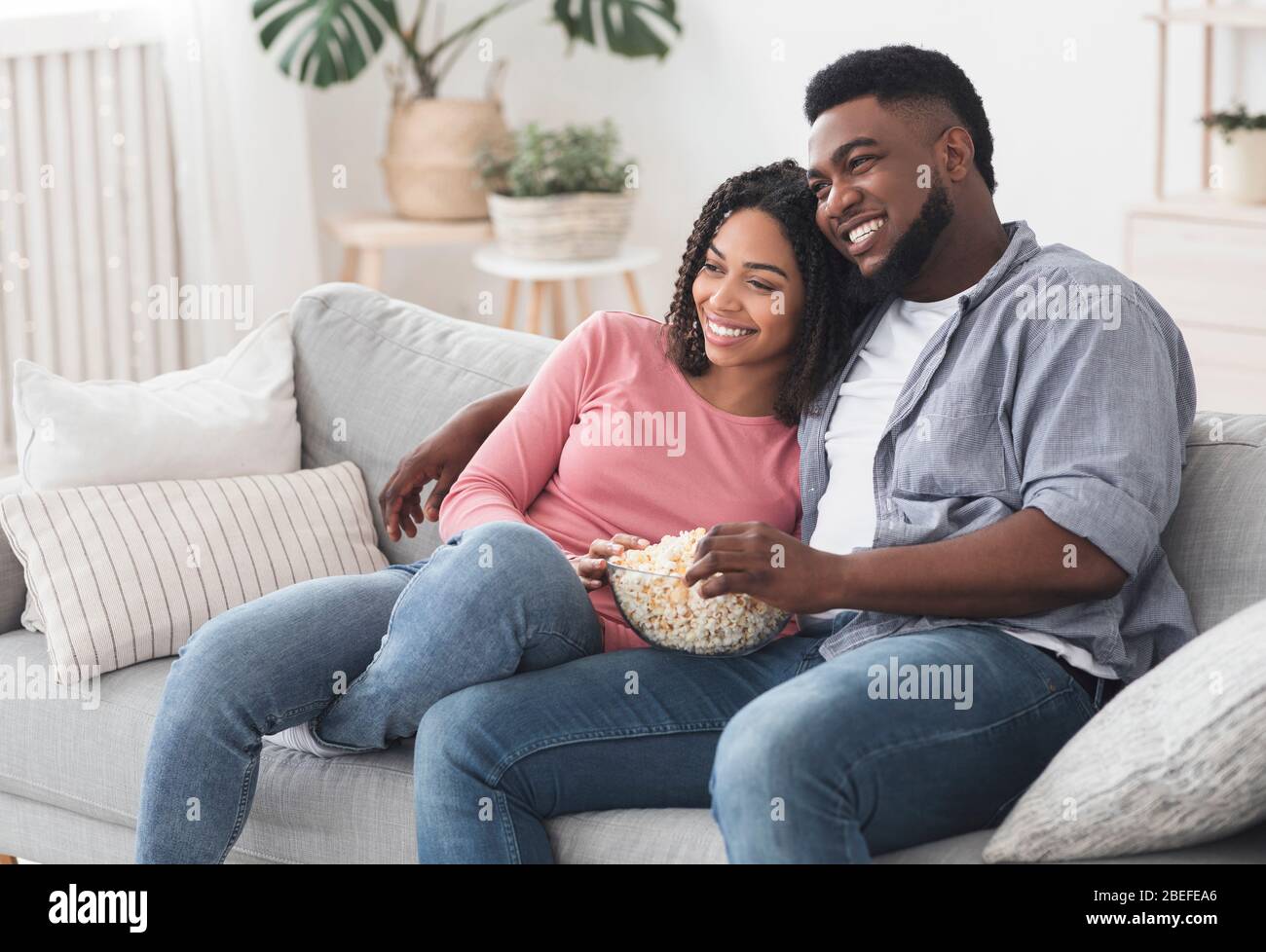 Relaxed african american couple watching tv, sitting on couch with ...