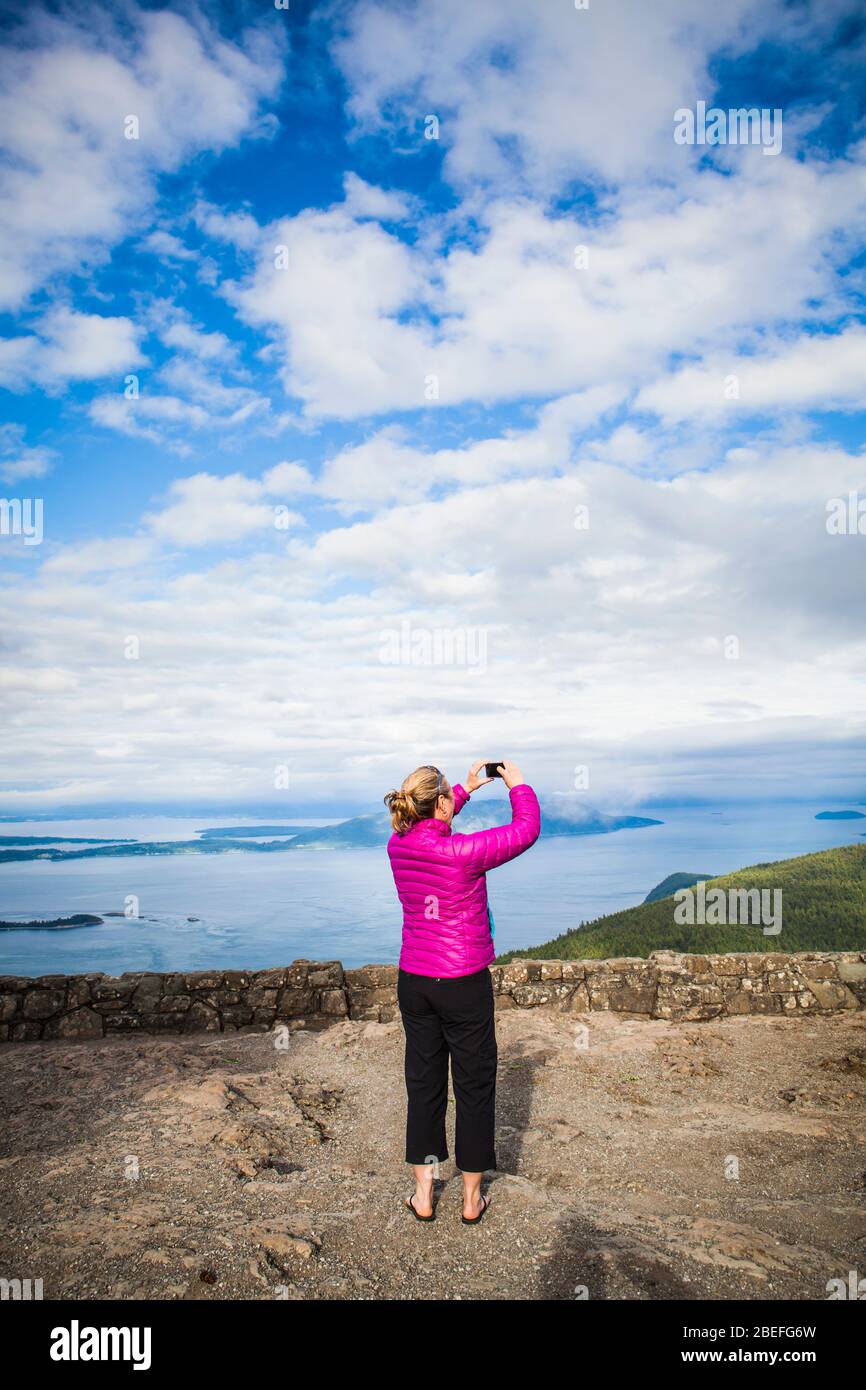 A woman taking pictures at the top of Mount Constitution on Orcas Island, Washington, USA. Stock Photo