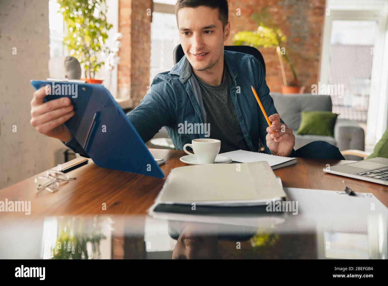 Creative workplace - organized work space as you like for inspiration. Man working in office in comfortable attire, relaxed position and messy table. Choose atmosphere you want - ideal clear or chaos. Stock Photo