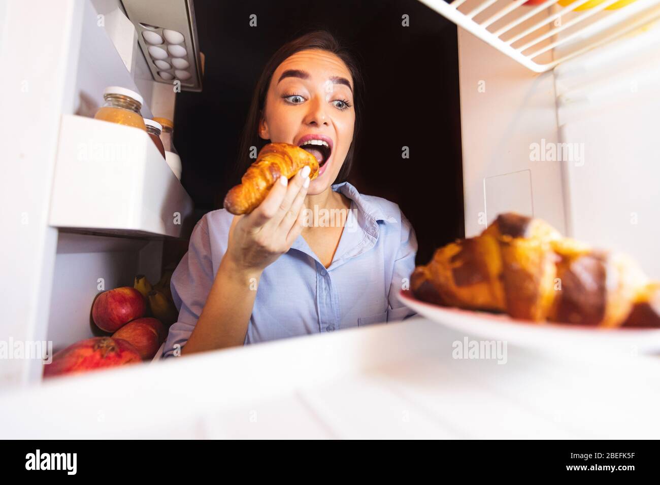 Young woman taking plate with croissants from fridge Stock Photo Alamy
