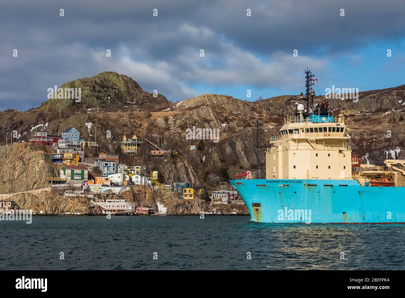 Maersk Dispatcher, an offshore tug and anchor handling supply vessel, passing The Battery, a colourful neighbourhood in St. John's, Newfoundland, Cand Stock Photo