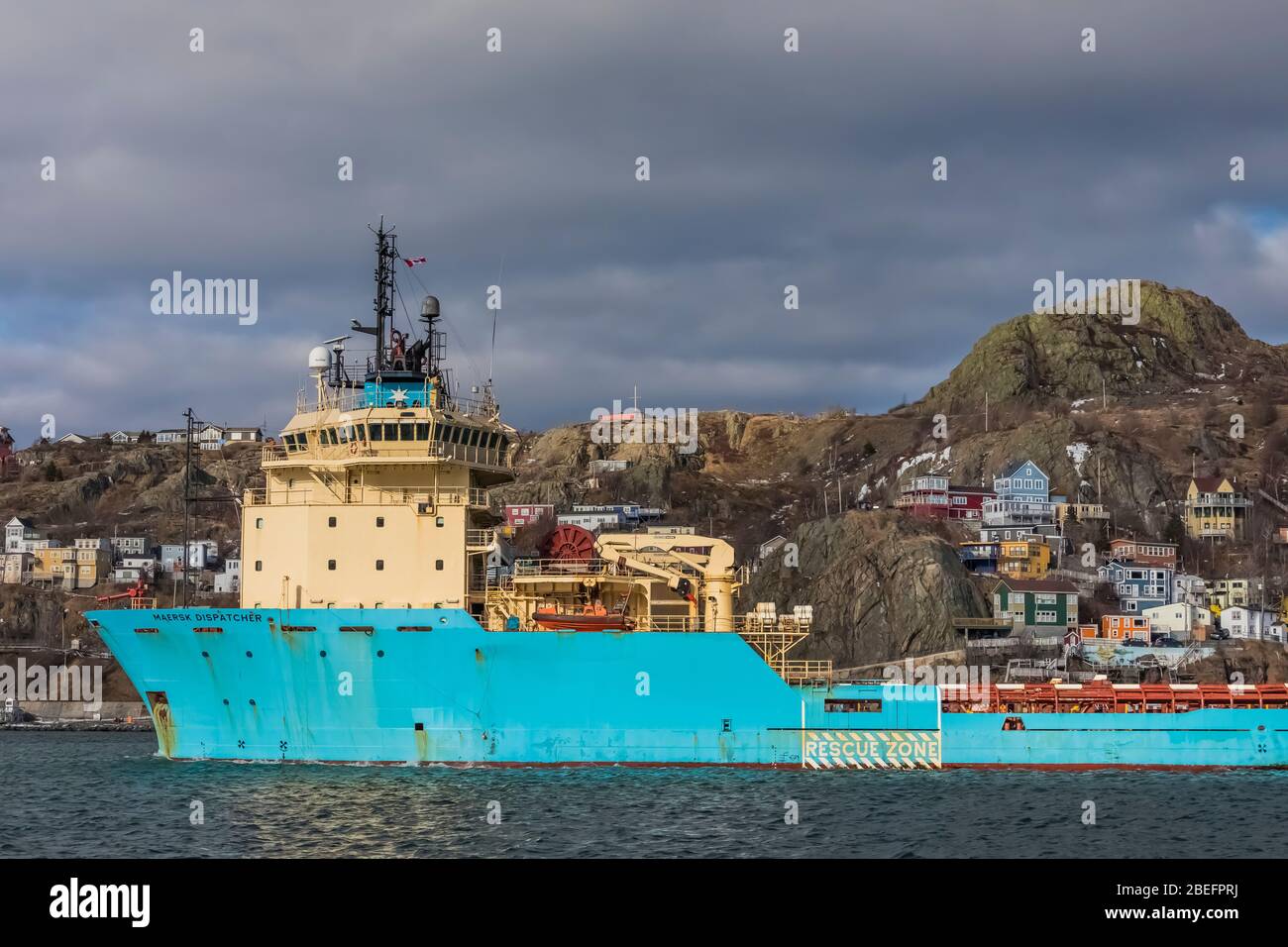Maersk Dispatcher, an offshore tug and anchor handling supply vessel, passing The Battery, a colourful neighbourhood in St. John's, Newfoundland, Cand Stock Photo
