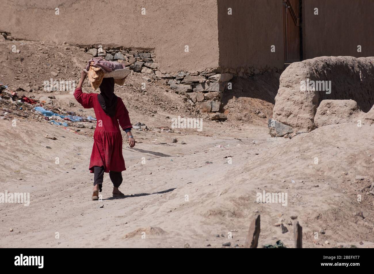 Kabul, Afghanistan - March 2004: Young girl walks home carrying bread Stock Photo
