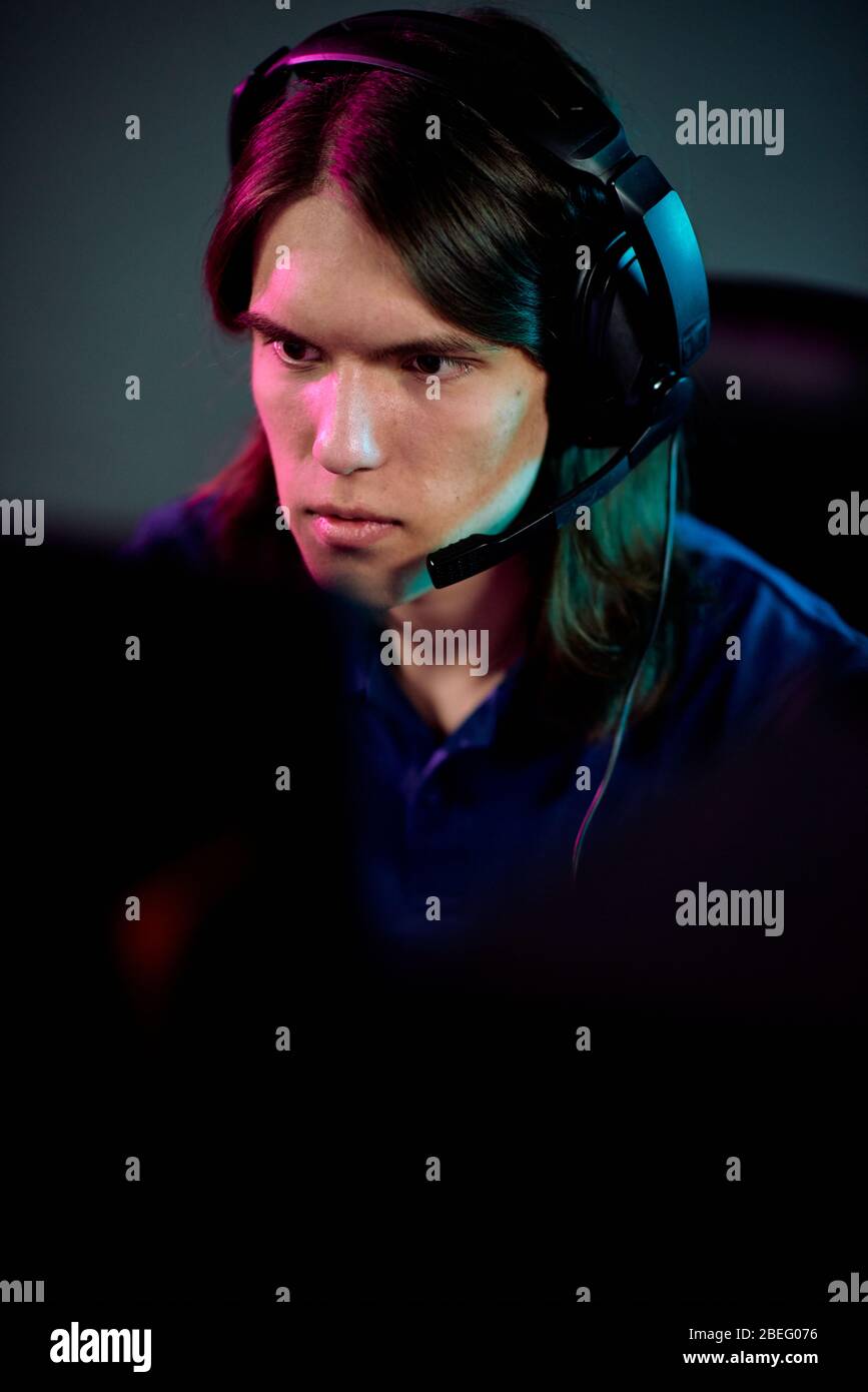 Focused Guy With Long Hair Using Headset With Microphone For Communication With Network Gamers While Playing Computer Game Stock Photo Alamy