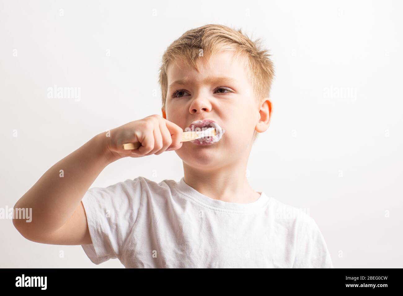 cute boy posing with bamboo toothbrush in his mouth, child brushes his