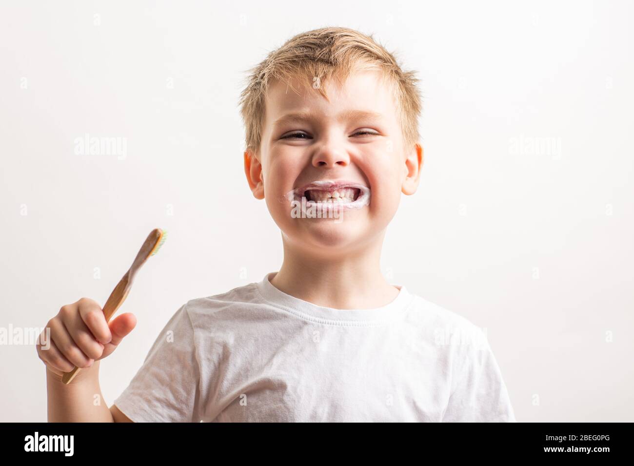 cute boy posing with bamboo toothbrush in his mouth, child brushes his