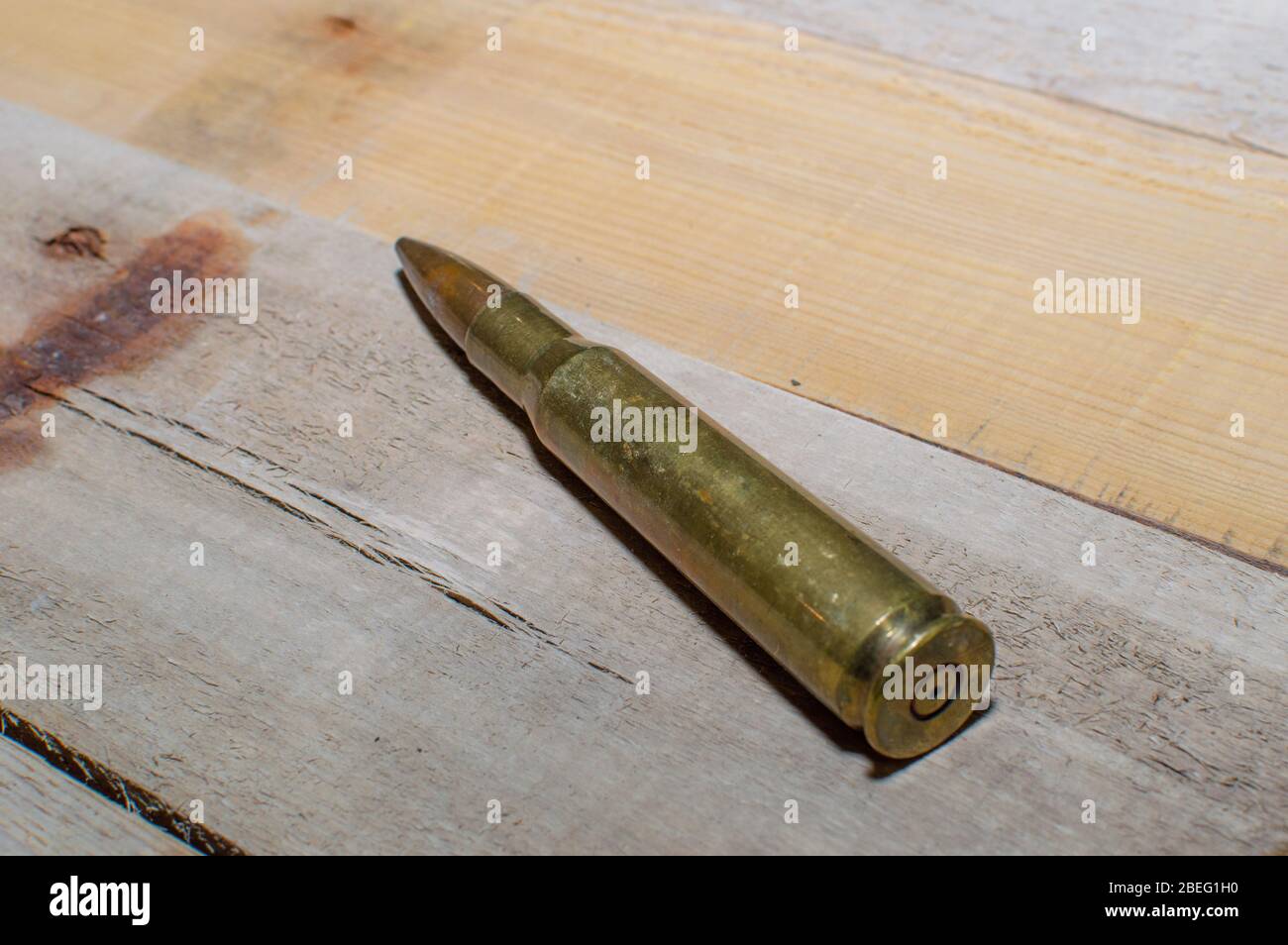 A 50 caliber rifle bullet laying on old barn wood. Stock Photo