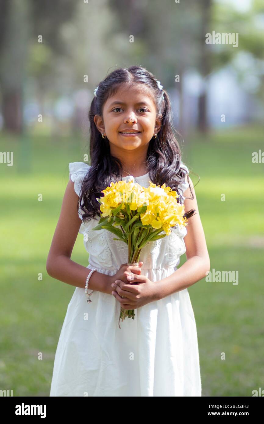 Little girl in white dress and with a cute bouquet of flowers in her ...