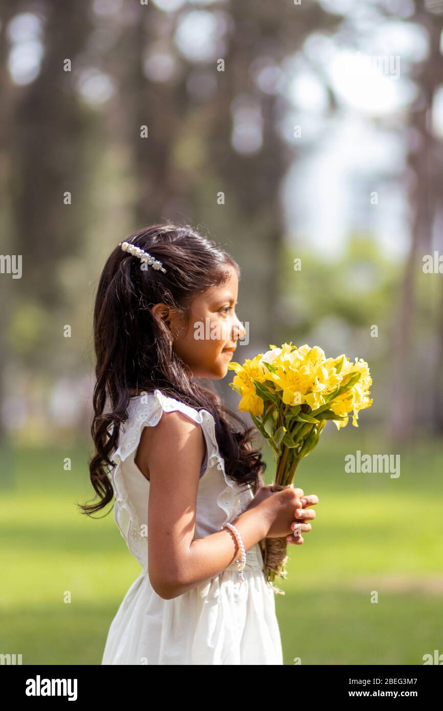 Little girl in white dress and with a cute bouquet of flowers in her ...