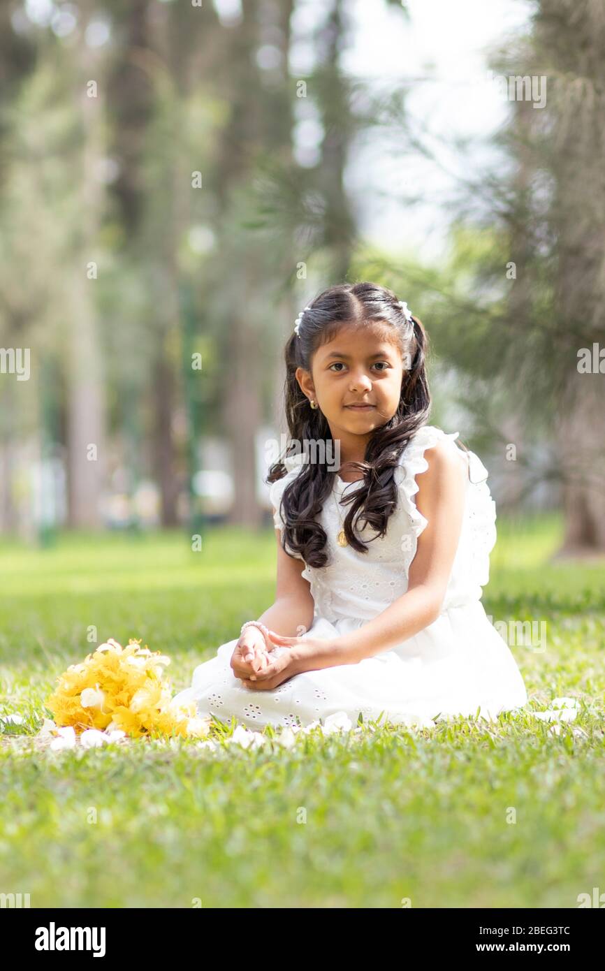 Little girl in white dress and with a cute bouquet of flowers in her ...