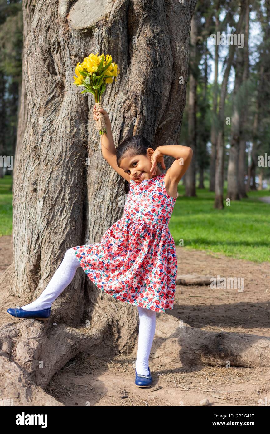 Little girl in dress celebrating in the park with a bouquet of flowers in her hand Stock Photo