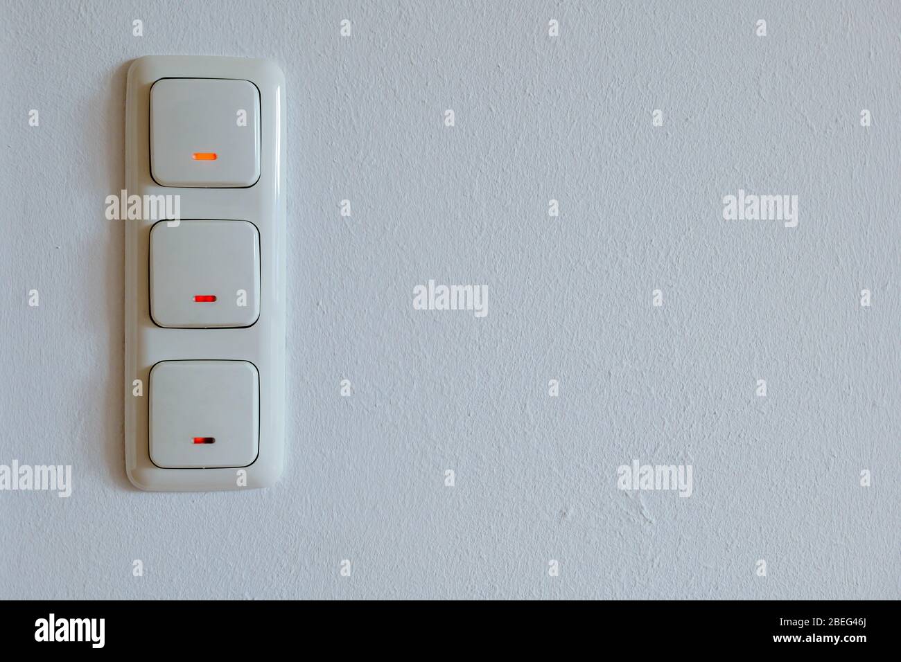Triple European light switches on white plaster interior wall Stock