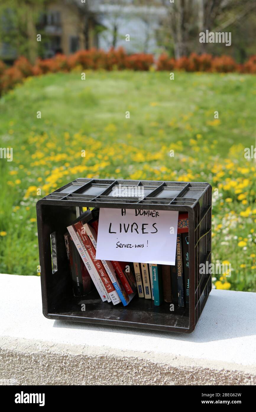 Caisse en plastique noire sur un muret comprenant des livres à donner. Saint-Gervais-les-Bains. Haute-Savoie. France. Stock Photo