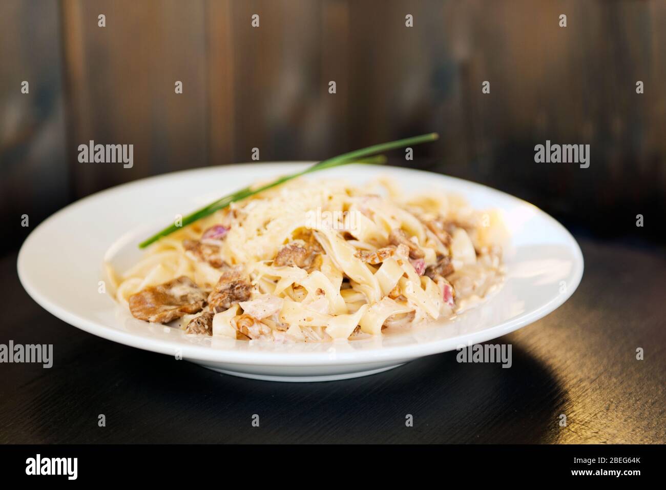 Plate of tagliatelli carbonara italian food in a rustic restaurant setting Stock Photo
