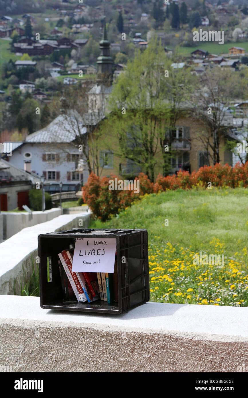 Caisse en plastique noire sur un muret comprenant des livres à donner. Saint-Gervais-les-Bains. Haute-Savoie. France. Stock Photo