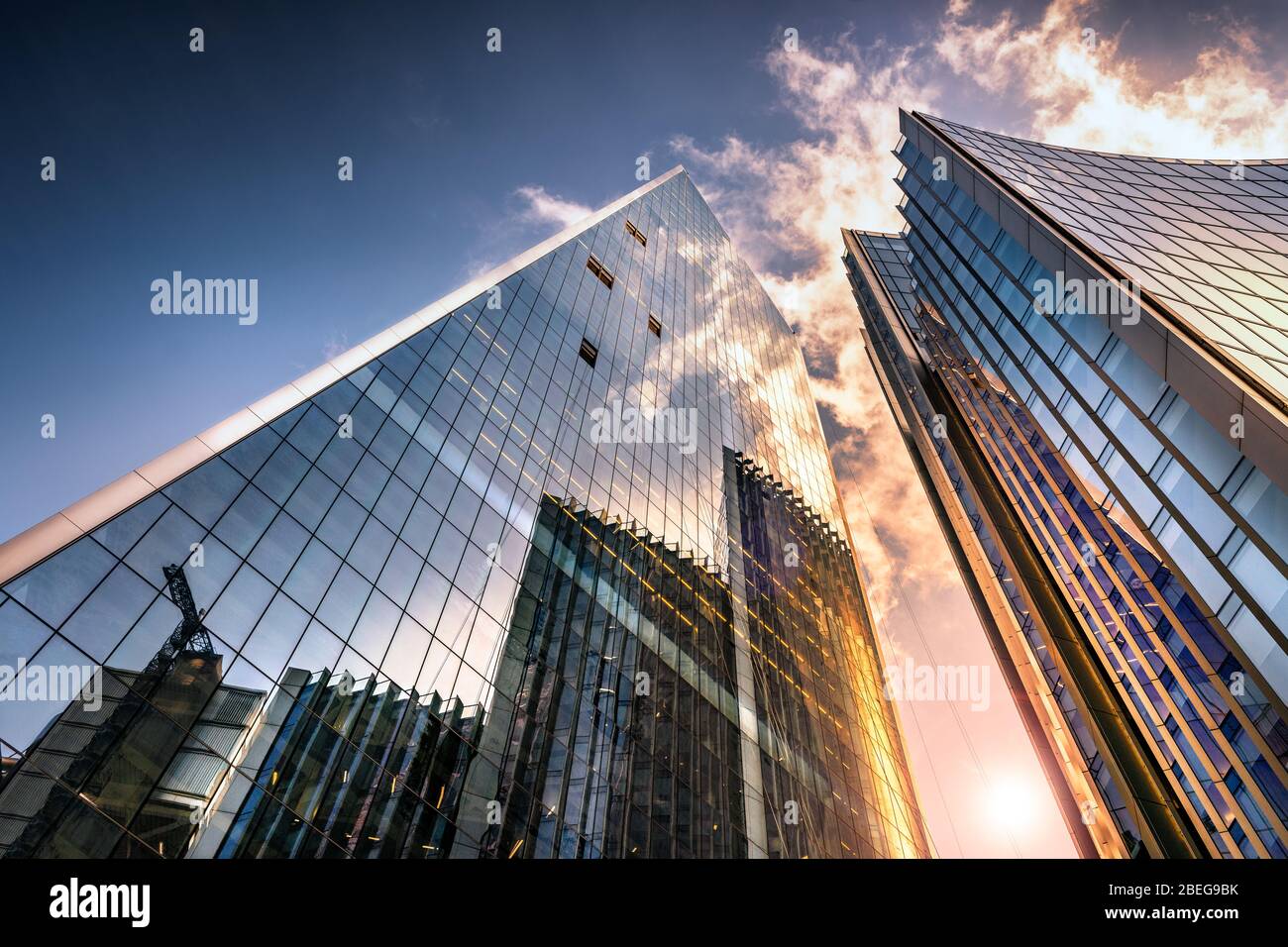 Low angle view of tall corporate glass skyscrapers reflecting a blue sky with white clouds Stock Photo