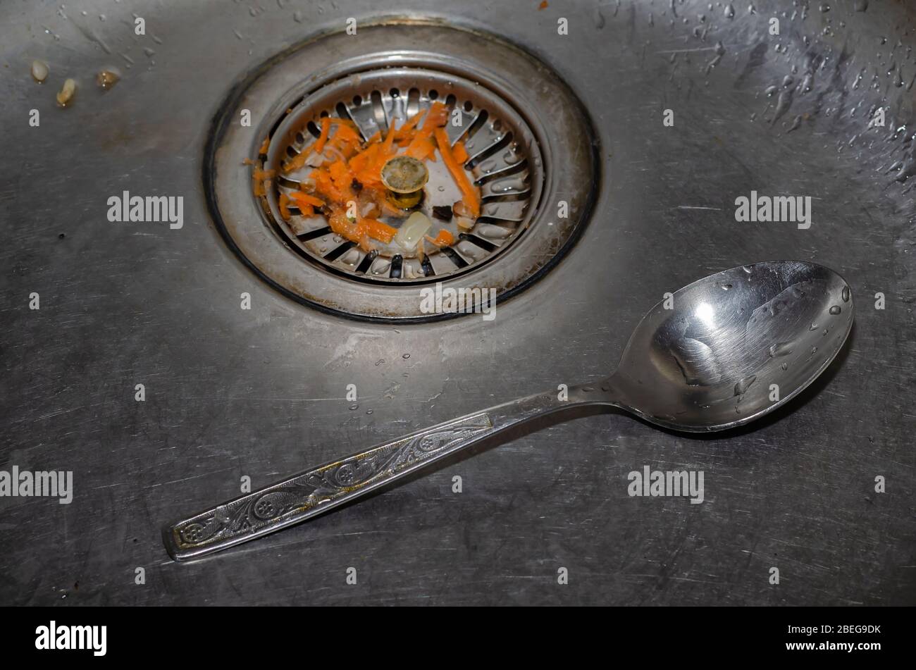 Dirty kitchen sink. Dirty spoon and food waste in the kitchen sink