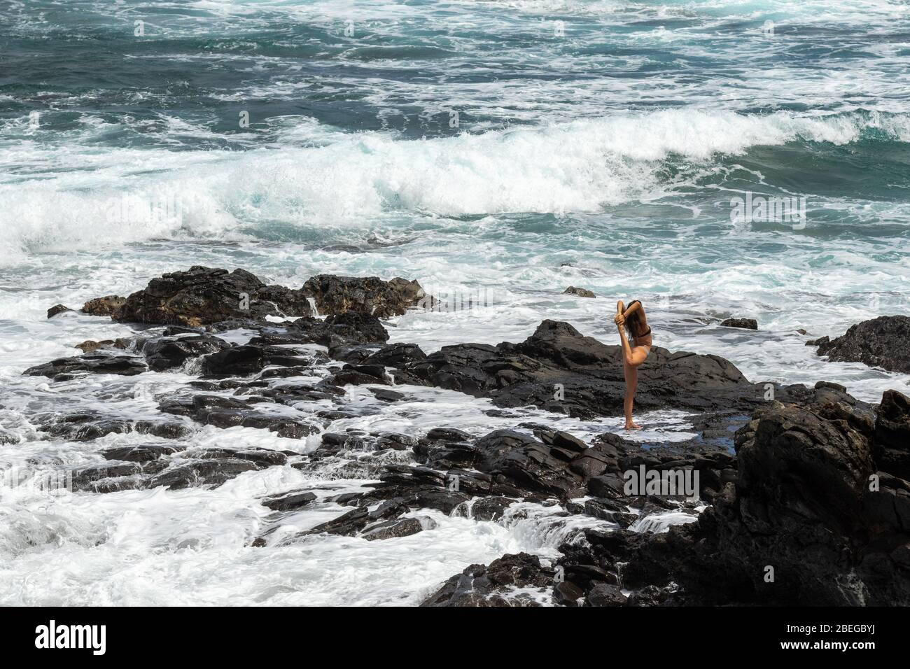 A woman does yoga along the coastline of Maui Stock Photo