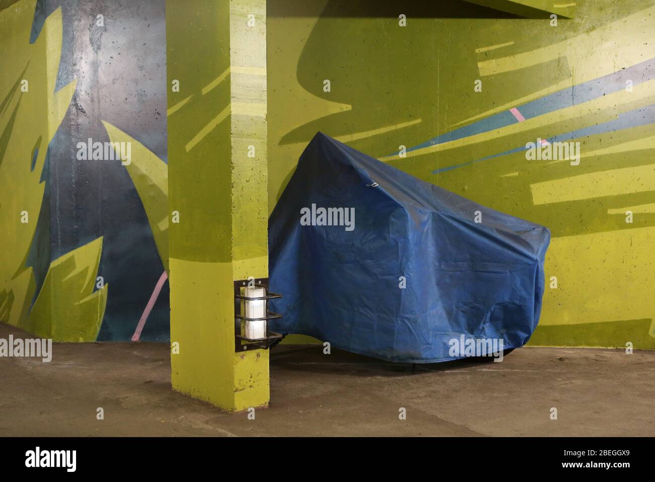 Moto recouverte d'une bâche en plastique bleue. Parking souterrain gratuit. 2KM3. Saint-Gervais-les-Bains. Haute-Savoie. France. Stock Photo