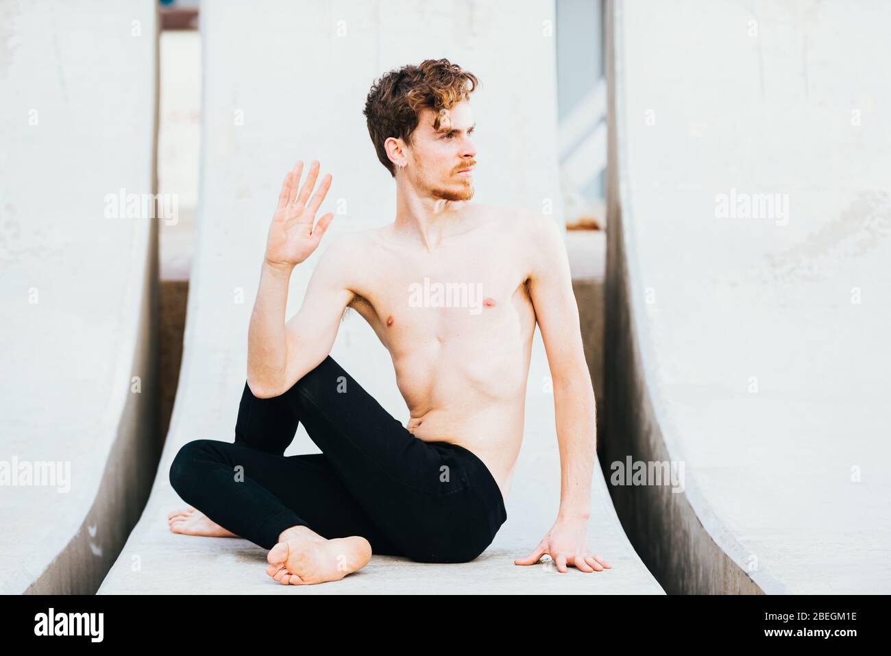 Young man  in the city in the yoga position ardha matsyendrasana stretching and relaxing her body and mind. Stock Photo