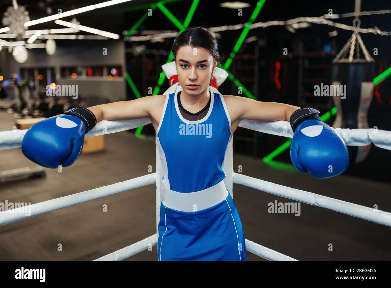 Woman in blue gloves in the corner of boxing ring Stock Photo