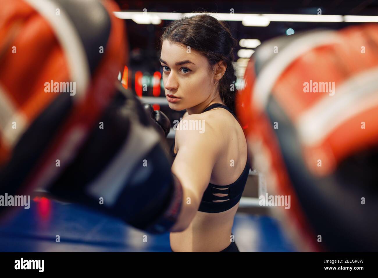 Woman in gloves boxing in the ring with trainer Stock Photo