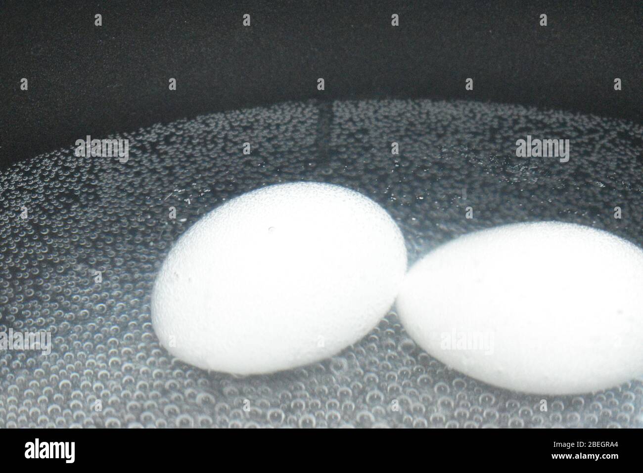 A closeup view of two white eggs in the boiling water and bubbles in the background.An Easter day special cooking photography with Nikon camera on apr Stock Photo