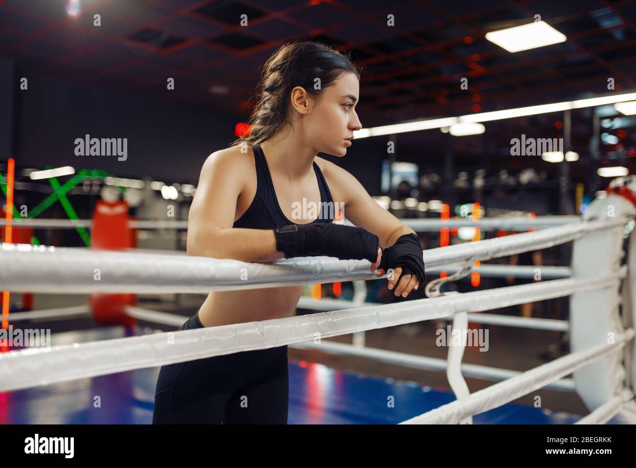 Woman in boxing bandages at the ropes on ring Stock Photo