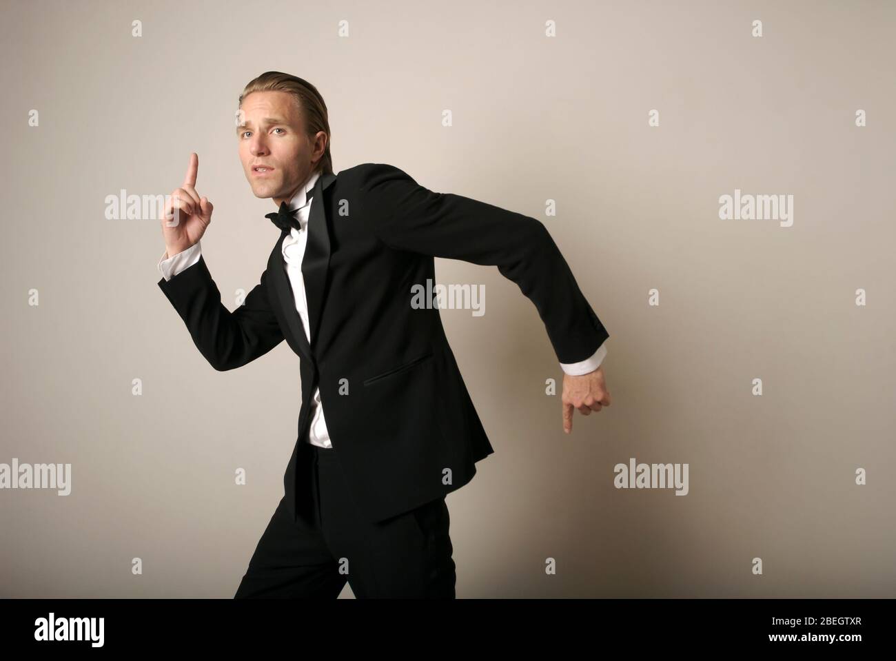 Cool young man in full tuxedo dancing with silly gestures Stock Photo