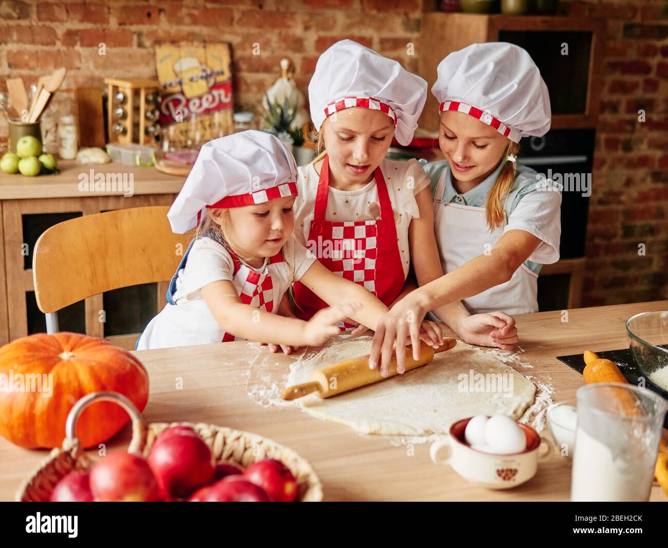 Three little chefs enjoying in the kitchen making cakes. Girls at the