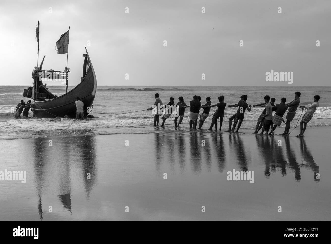 Men Hauling Moon Shaped Fishing Boats in a Fishing Village South of Cox's Bazar Stock Photo
